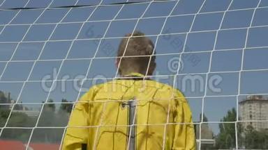 足球比赛中，一名身穿黄色制服的足球守门员站在门口，背上有一个数字
